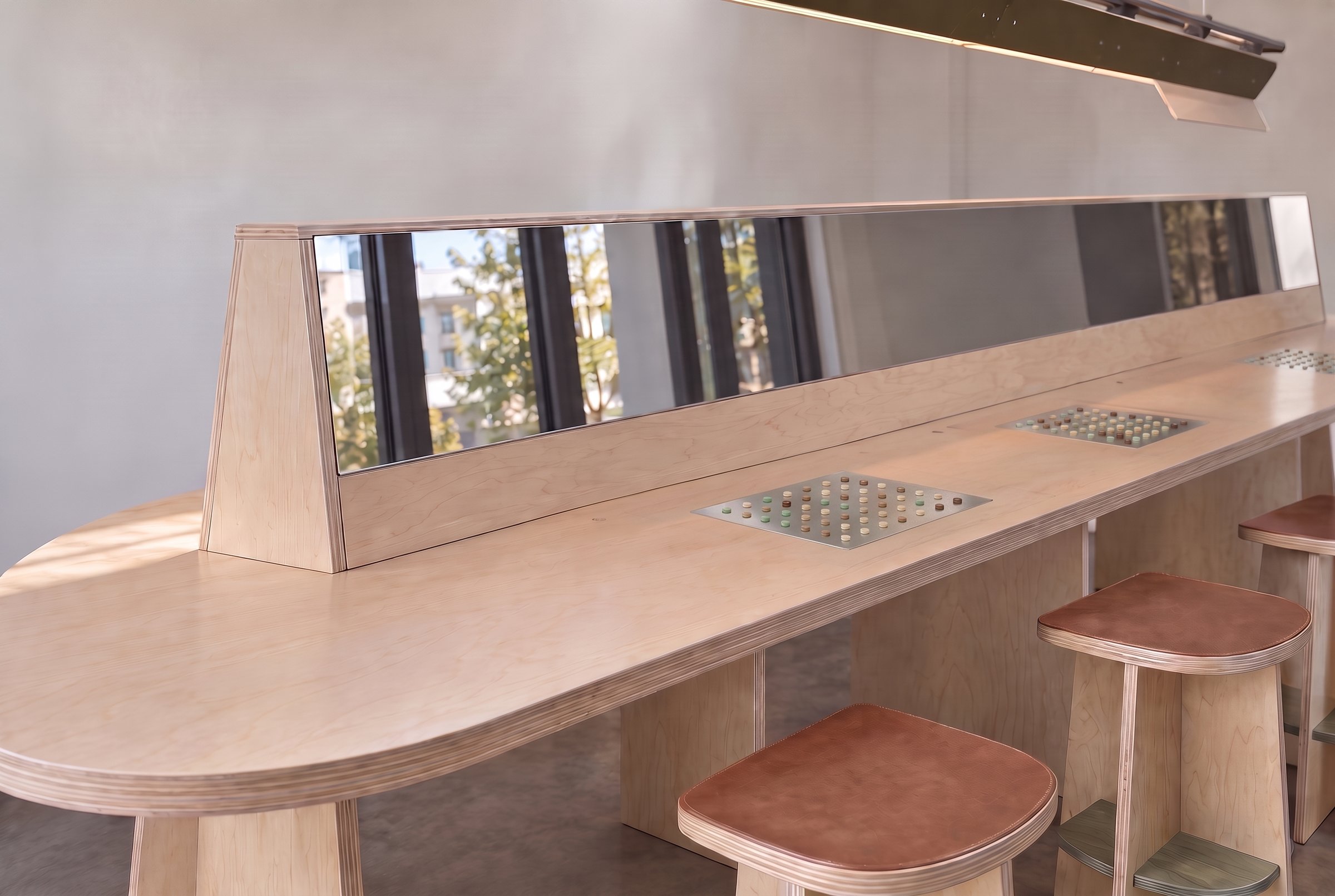 The Fragrance Studio’s long maple bench with a mirrored divider, note trays set into the top and leather-topped stools