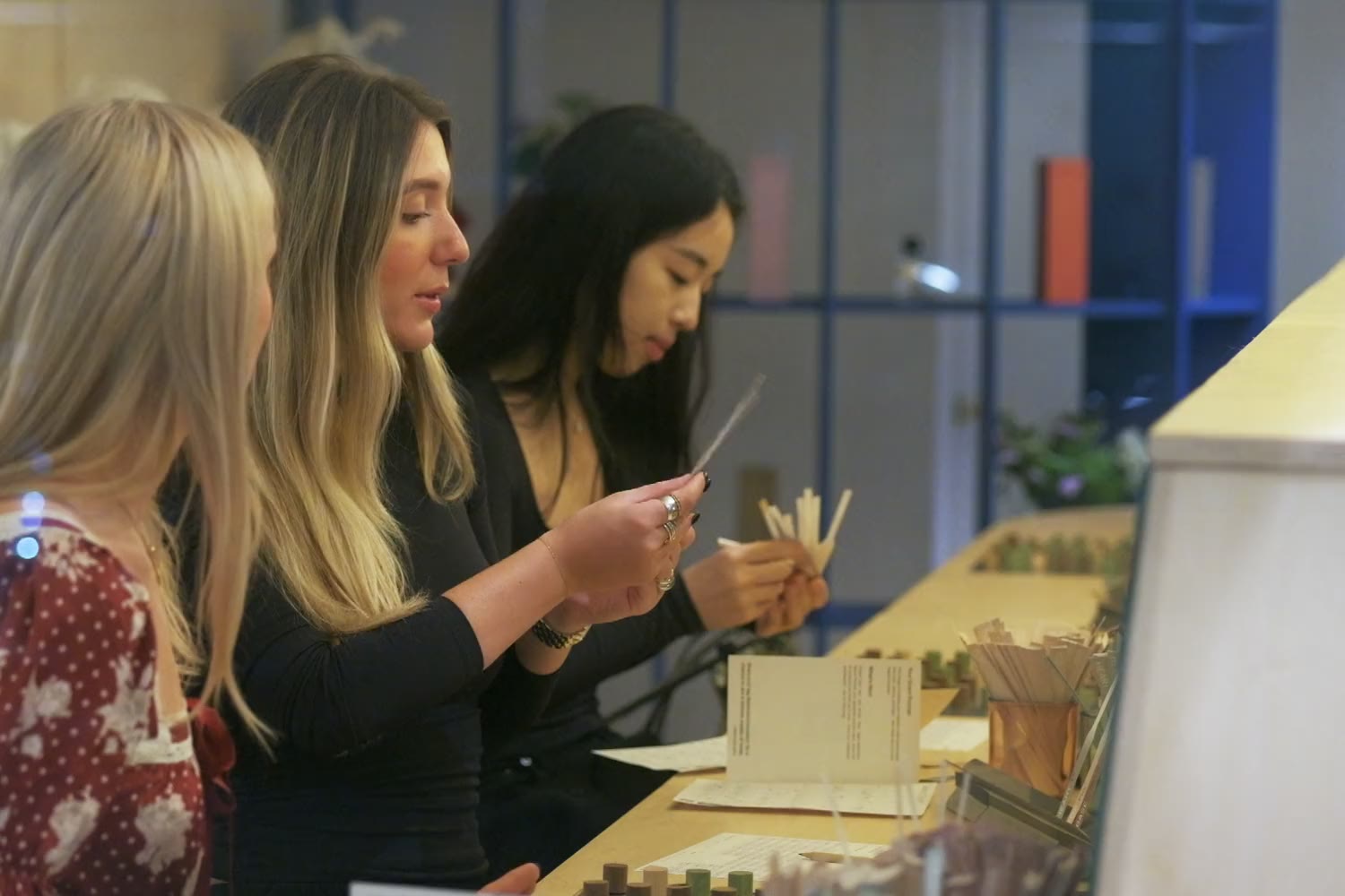 Three guests at the Fragrance Studio bench smelling scent strips together